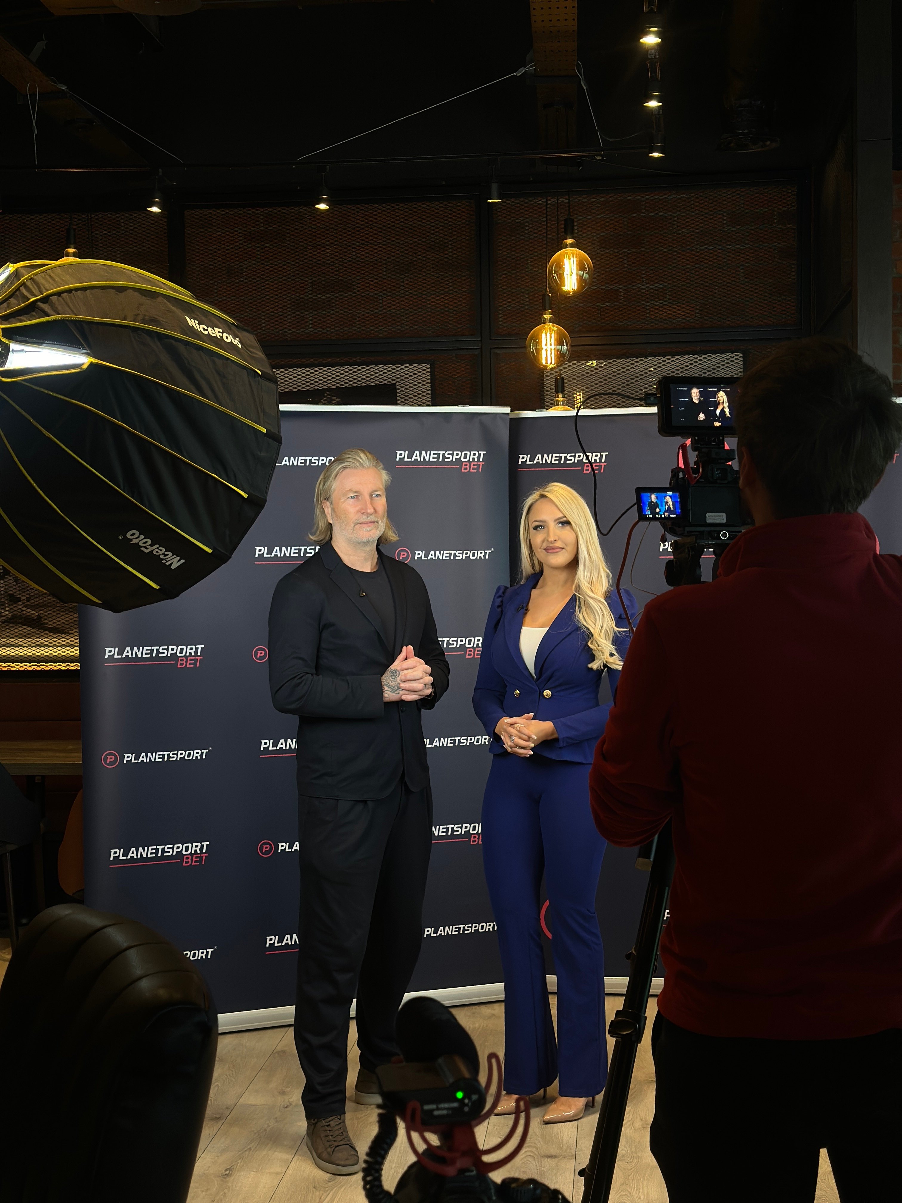 Robbie Savage and Emma Jones filming with a Planet Sport Bet backdrop
